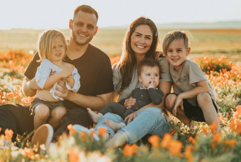 3 women and 2 men sitting on green grass field during daytime